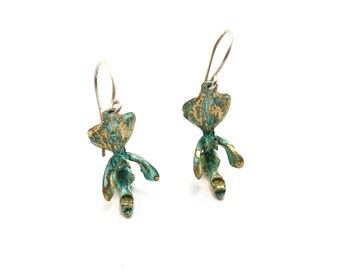May include: A pair of earrings featuring a green and gold abstract design. The earrings are made of metal and have a dangling style.