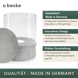 May include: A gray concrete candle holder with a glass cylinder. The candle holder has the text "beske" on the side. The text "Handarbeit - Made in Germany" is on a green background. The text "QUALIT&Auml;T - MADE IN GERMANY" is on a green background.