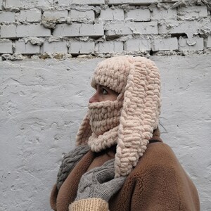 Puede incluir: Un pasamonta&ntilde;as beige tejido con largas orejas de conejo flexibles. El pasamonta&ntilde;as cubre la cabeza, el cuello y la parte inferior de la cara, con una bufanda y guantes a juego. El gorro est&aacute; hecho de un hilo grueso y texturizado.