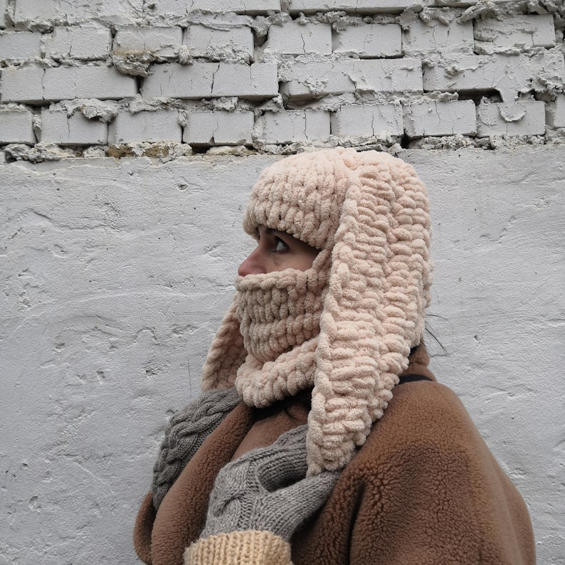Puede incluir: Un pasamonta&ntilde;as beige tejido con largas orejas de conejo flexibles. El pasamonta&ntilde;as cubre la cabeza, el cuello y la parte inferior de la cara, con una bufanda y guantes a juego. El gorro est&aacute; hecho de un hilo grueso y texturizado.