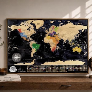 May include: A rectangular scratch-off world map poster in a wooden frame featuring a black background with gold foil continents. The map displays colorful country borders, a compass rose, and a row of national flags at the bottom with the text Travel Map.
