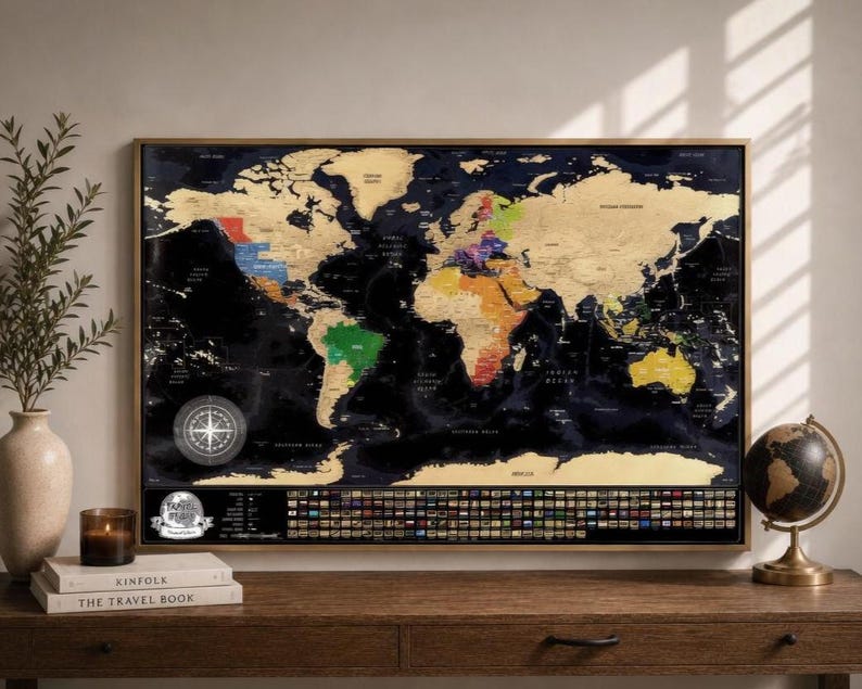 May include: A rectangular scratch-off world map poster in a wooden frame featuring a black background with gold foil continents. The map displays colorful country borders, a compass rose, and a row of national flags at the bottom with the text Travel Map.