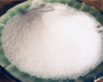 May include: A white granulated sugar in a green and white ceramic dish.
