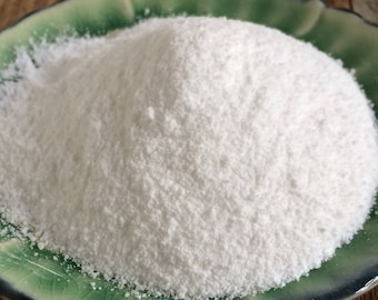 May include: A white powder in a green and blue ceramic dish. The powder is finely ground and has a smooth texture.