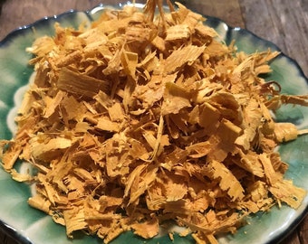 May include: A pile of yellow wood shavings on a green and white patterned plate.