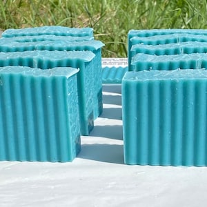 May include: A stack of blue soap bars with a ridged texture. The soap bars are arranged in a staggered pattern.