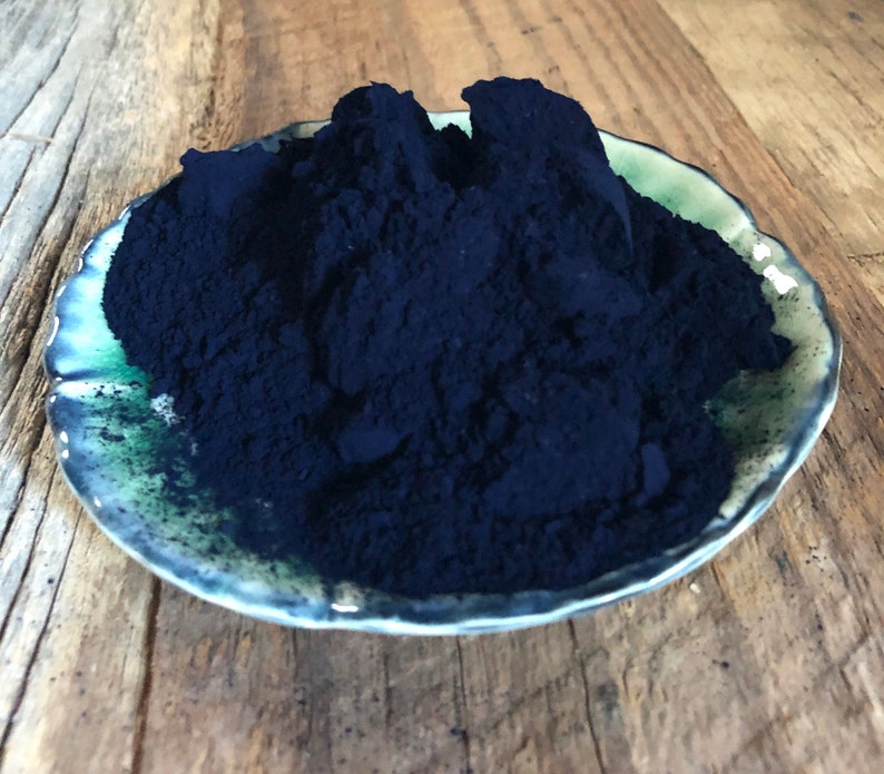 Puede incluir: Un peque&ntilde;o plato de cer&aacute;mica azul lleno de un mont&oacute;n de polvo azul oscuro.