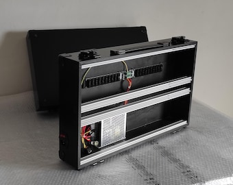 以下が含まれることがあります： 内蔵電源と2段の収納スペースを備えた黒いペダルボードケース。ケースにはハンドルと電源コードが付いています。