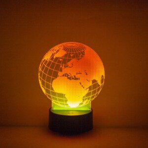 May include: A globe-shaped night light with a grid pattern and a yellow and orange glow. The base is black.