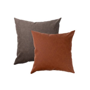 May include: Two decorative throw pillows, one brown and one orange. The pillows are made of a soft, textured fabric.