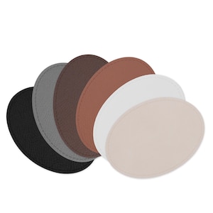 May include: A collection of six oval-shaped coasters in various colors: black, gray, brown, tan, white, and light pink. Each coaster has a stitched edge, and they are arranged in a fan shape, showcasing their different hues and textures.