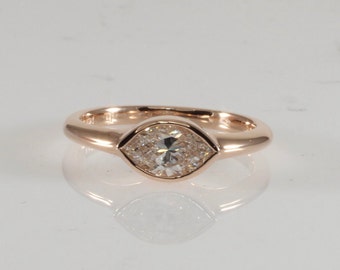 Könnte beinhalten: Ein Ring aus Roségold mit einem Marquise-Diamanten in einer Zargenfassung.