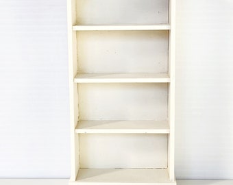 May include: White wooden bookshelf with four shelves and a decorative top. The bookshelf is empty.