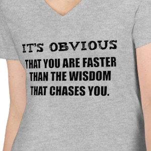 Puede incluir: Camiseta gris de cuello en V con el texto "It's obvious that you are faster than the wisdom that chases you."