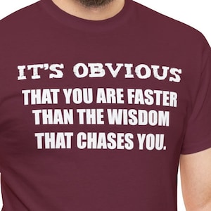 Puede incluir: Camiseta color burdeos con texto blanco que dice "Es obvio que eres más rápido que la sabiduría que te persigue."