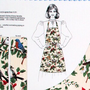 May include: A white apron with a colorful bird and floral pattern. The apron has two ties and is shown being worn by a person. The text "tie end" is printed on the apron.