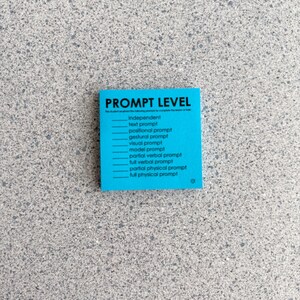 May include: A square bright blue sticky note featuring the black text PROMPT LEVEL followed by a checklist of options including independent, text prompt, positional prompt, gestural prompt, visual prompt, model prompt, partial verbal prompt, full verbal prompt, partial physical prompt, and full physical prompt.