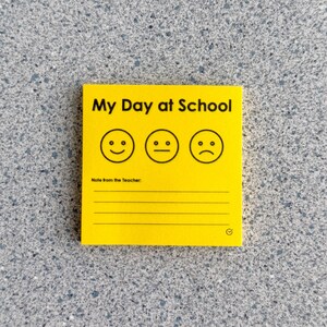 May include: A square yellow notepad featuring the black text My Day at School at the top. Below the text are three black line-art faces showing happy, neutral, and sad expressions. The bottom section includes the text Note from the Teacher and lines.