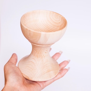 May include: A light wood pedestal bowl with a wide, shallow bowl and a turned base.