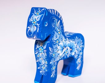 May include: A blue wooden horse figurine with white and gold floral designs painted on it.