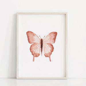 May include: A framed print of a watercolor painting of a butterfly with a light brown color.