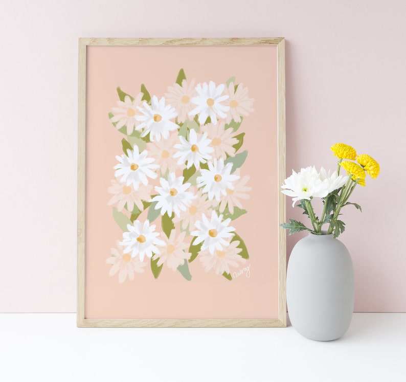 May include: A framed print of a floral illustration featuring a cluster of white and pink daisies on a light pink background. The print is in a light wood frame.