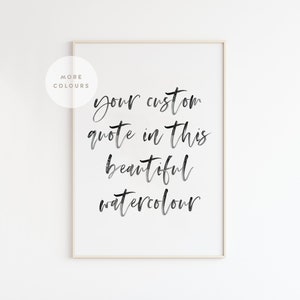 May include: A framed print with the text "your custom quote in this beautiful watercolour" in elegant black script. The print is set against a white background, with a neutral-toned frame. A circular graphic reads "More Colours".