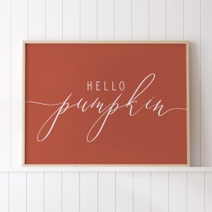 May include: A framed print with a burnt orange background and white cursive text that reads "HELLO pumpkin".