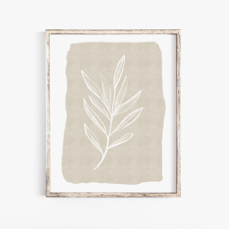 May include: A framed print featuring a beige background with a white line drawing of a branch and leaves.