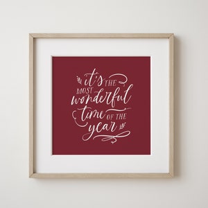 May include: A framed print with a red background and white text that reads "it's the most wonderful time of the year".