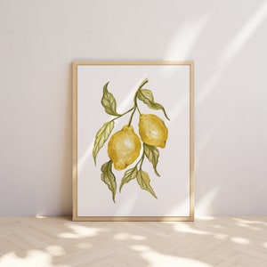 Pode incluir: Pintura em aquarela de dois lim&otilde;es em um galho com folhas verdes. A obra de arte &eacute; emoldurada em uma moldura de madeira clara e exibida contra uma parede branca. Os lim&otilde;es s&atilde;o amarelos e as folhas s&atilde;o verdes.