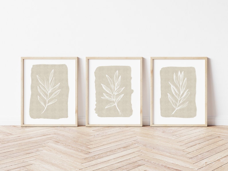 May include: Three framed prints with a beige background and a white line drawing of a leaf branch on each print.