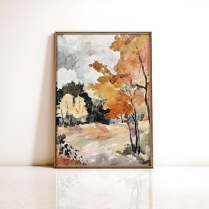 May include: Watercolor painting of a landscape with trees in autumn colors. The artwork features a mix of orange, yellow, and green hues, with a cloudy gray sky. The painting is framed in a gold-colored frame.