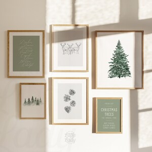 May include: A set of six framed prints with a Christmas theme. The prints feature a watercolour illustration of a Christmas tree, a black and white illustration of pine cones, a black and white illustration of three deer, a watercolour illustration of a forest, a handwritten calligraphy print with the words "Dasher, Dancer, Prancer, Vixen, Comet, Cupid, Donner, Blitzen, Rudolph", and a green sign with the text "Fresh Cut Christmas Trees Fir Spruce Pine Hot Cocoa Sleigh Rides Candy Canes".