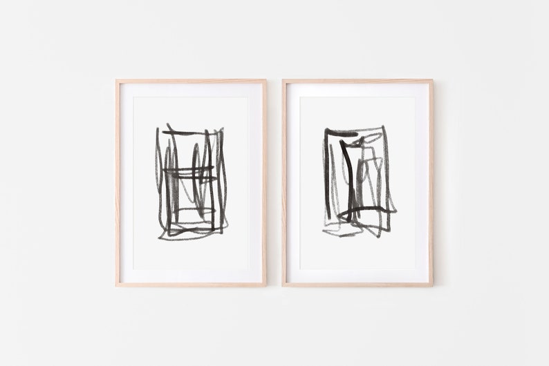 May include: Two framed black and white abstract art prints with a minimalist style. Each print features a square shape with black lines and strokes.