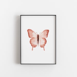 May include: A framed print of a watercolor painting of a butterfly with a light pink color.