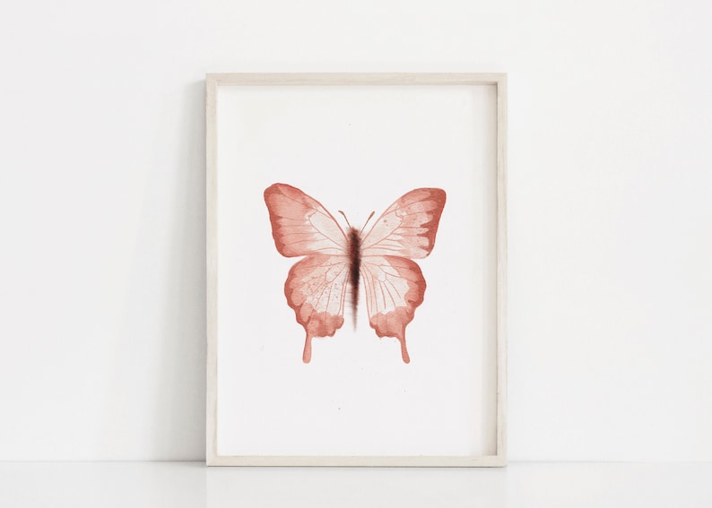 May include: A framed print of a watercolor painting of a butterfly with a light brown color.