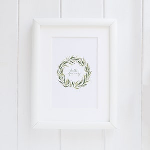 May include: A white framed print with a green and white floral wreath and the text "hello spring" in cursive.
