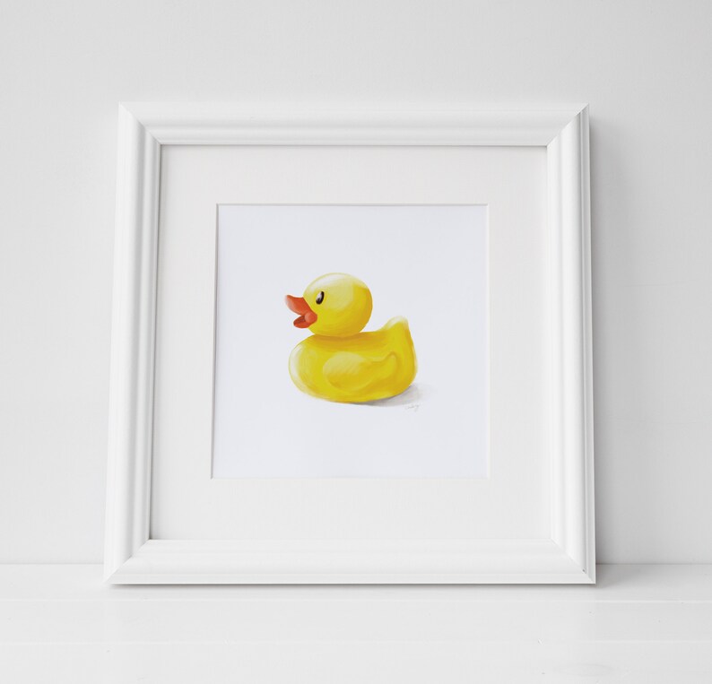 May include: A framed illustration of a yellow rubber ducky with an orange beak and eyes. The ducky is facing to the right and is sitting on a white background.
