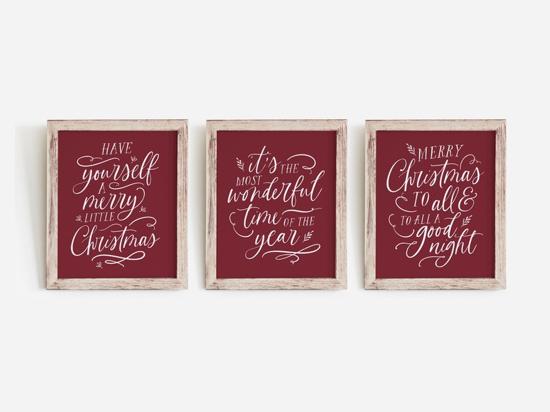 May include: Three framed signs with white calligraphy on a burgundy background. The signs read "Have yourself a merry little Christmas", "It's the most wonderful time of the year", and "Merry Christmas to all & to all a good night".