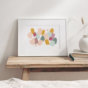 May include: A framed abstract print with a white background and colorful geometric shapes in shades of pink, yellow, green, and red.