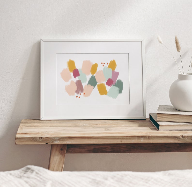 May include: A framed abstract print with a white background and colorful geometric shapes in shades of pink, yellow, green, and red.