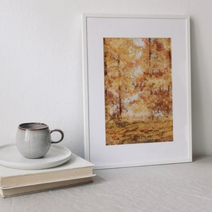 May include: A white framed print of a painting depicting a forest scene with trees in shades of yellow, orange, and brown. The trees are in the background, and the foreground is a field of grass.