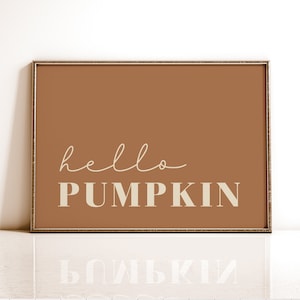 May include: A framed print with a brown background and the text "hello pumpkin" in a cream color.