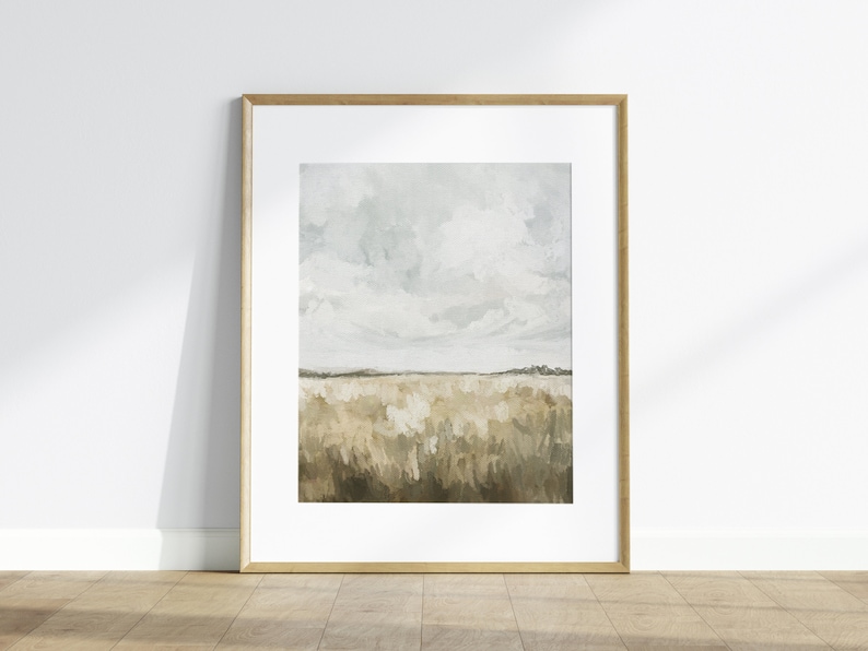 May include: A framed abstract landscape painting with a light blue sky and white clouds over a field of brown and green brushstrokes.