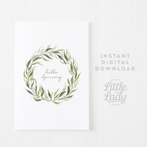 May include: A printable digital download featuring a watercolor wreath of green leaves and white flowers with the text "hello spring" in the center.