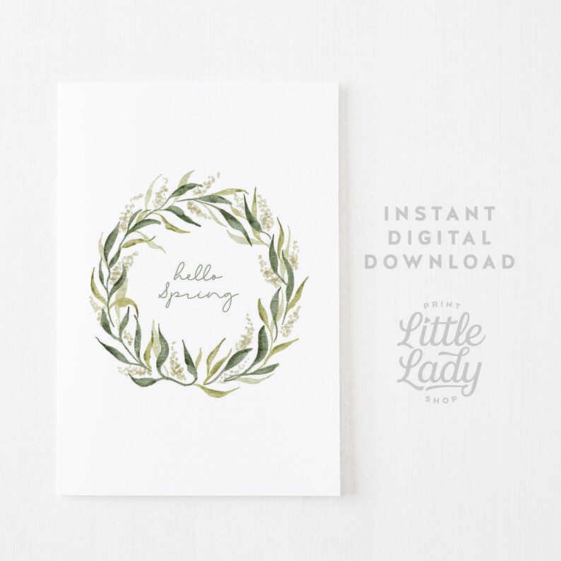 May include: A printable digital download featuring a watercolor wreath of green leaves and white flowers with the text "hello spring" in the center.