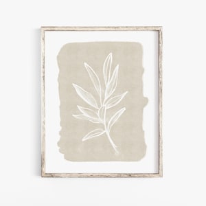 May include: A framed print featuring a white line drawing of a leafy branch on a beige background.