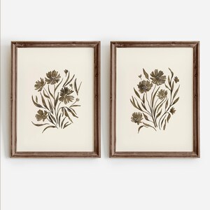 May include: Two framed prints with a watercolor style design of brown flowers and leaves on a white background.