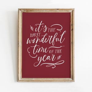 May include: A framed print with a red background and white text that reads "it's the most wonderful time of the year".